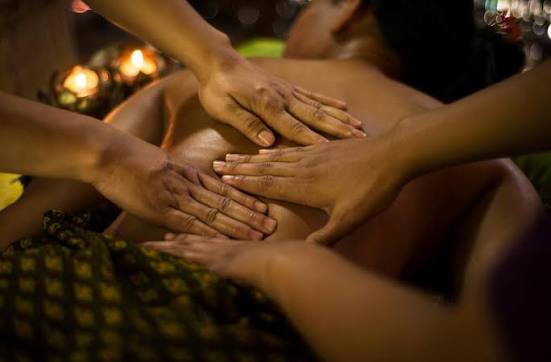 Multiple therapist hands working together during a four hands massage treatment